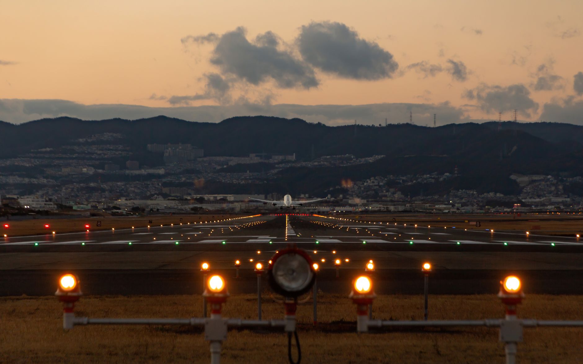 An aircraft landing at Osaka at dusk with the city skyline behind