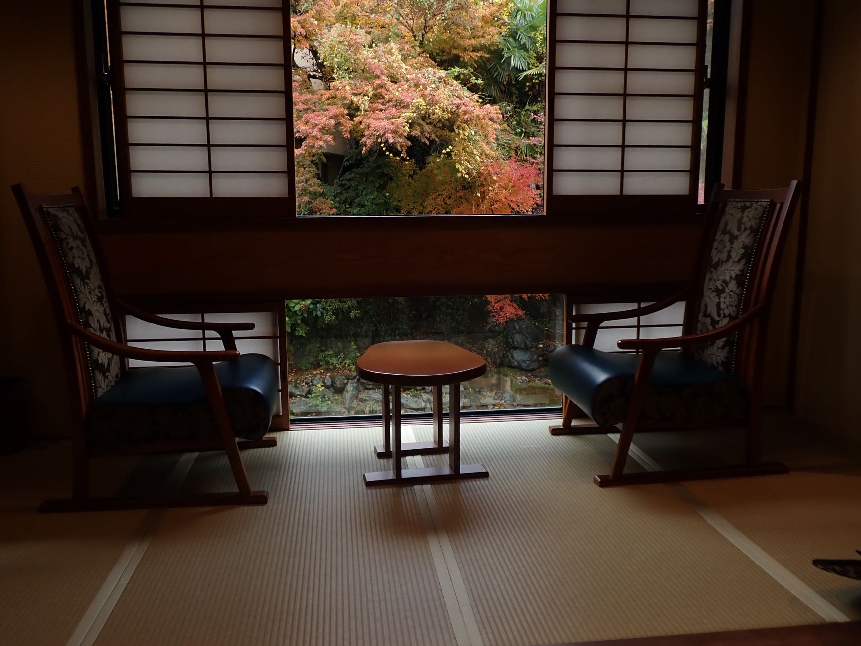 Tatami-Zimmer eines Ryokan mit Fenster auf Herbstlaub