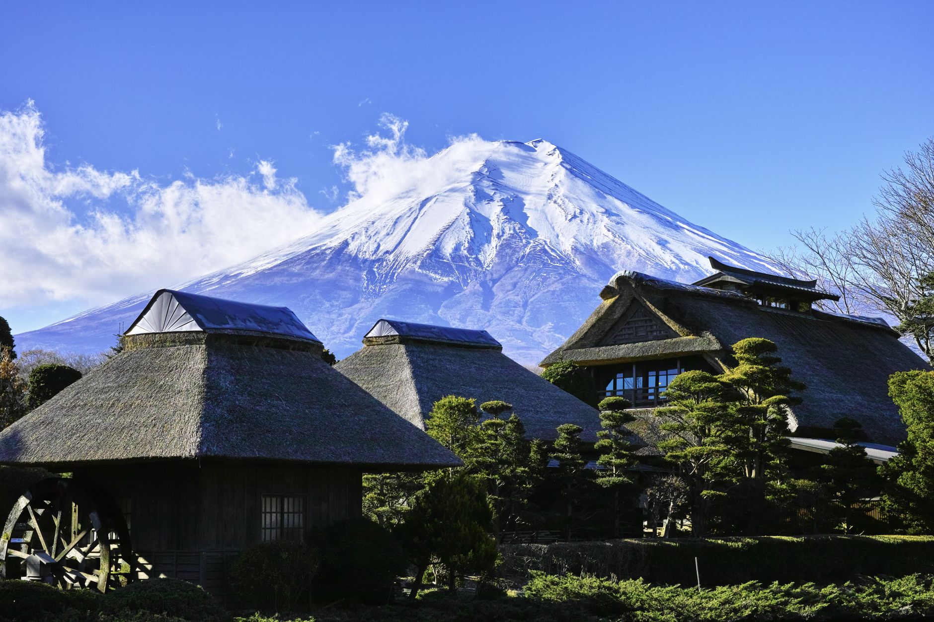 Thatched farmhouses and water wheel at Oshino Hakkai below snow-capped Mt. Fuji
