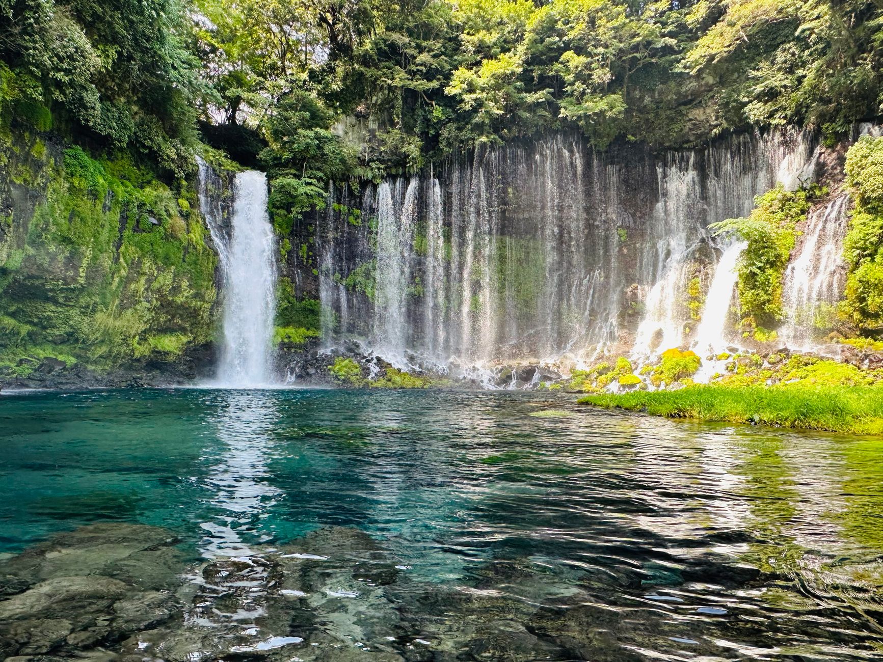Curtain of springwater streams pouring into the turquoise pool at Shiraito Falls, Fujinomiya
