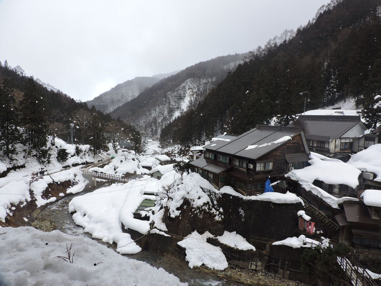 Illustrative photo: Residential houses covered with hoarfrost located near creek amidst forested mountains on snowy ground on cold winter day in countryside