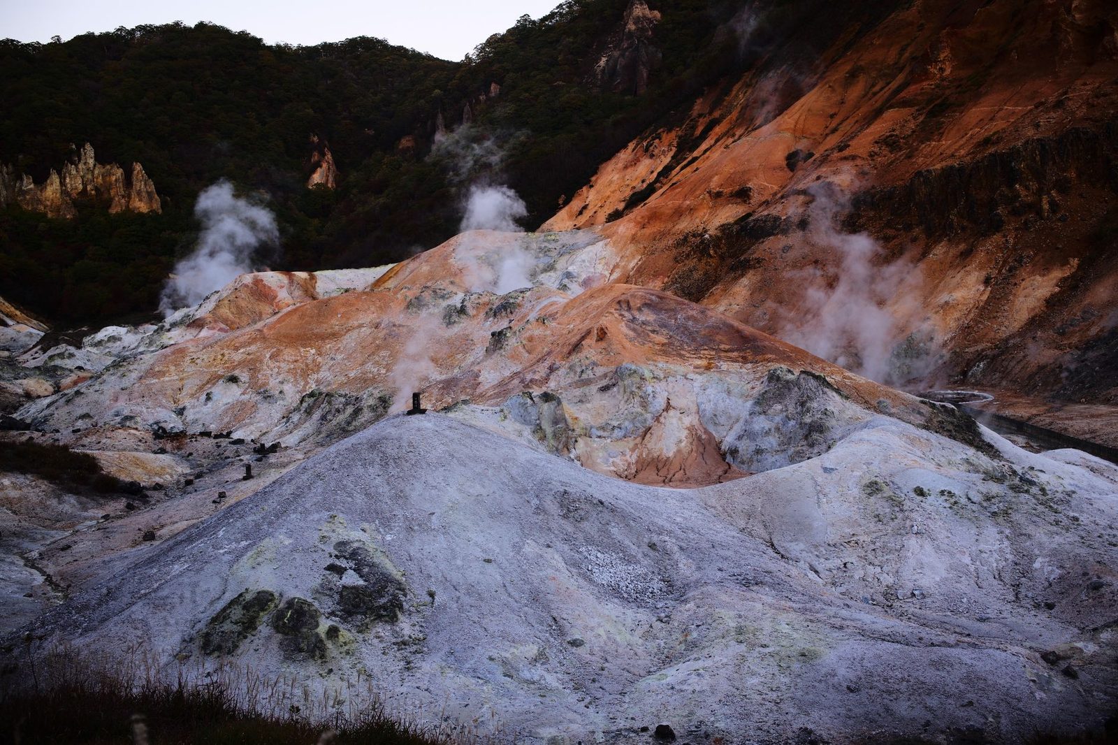 Illustrative photo: Dramatic geothermal terrain with steaming vents and colorful rock formations.