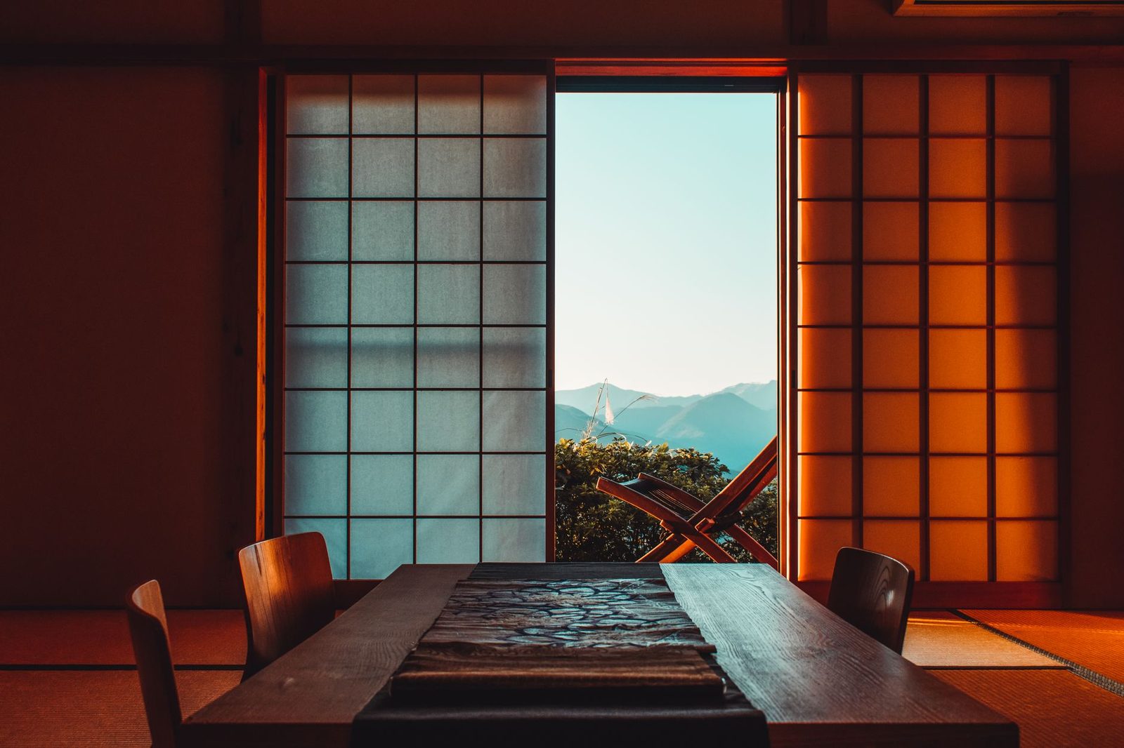 Illustrative photo: A serene Japanese room featuring shoji screens and a mountain view, illuminated by warm lighting.