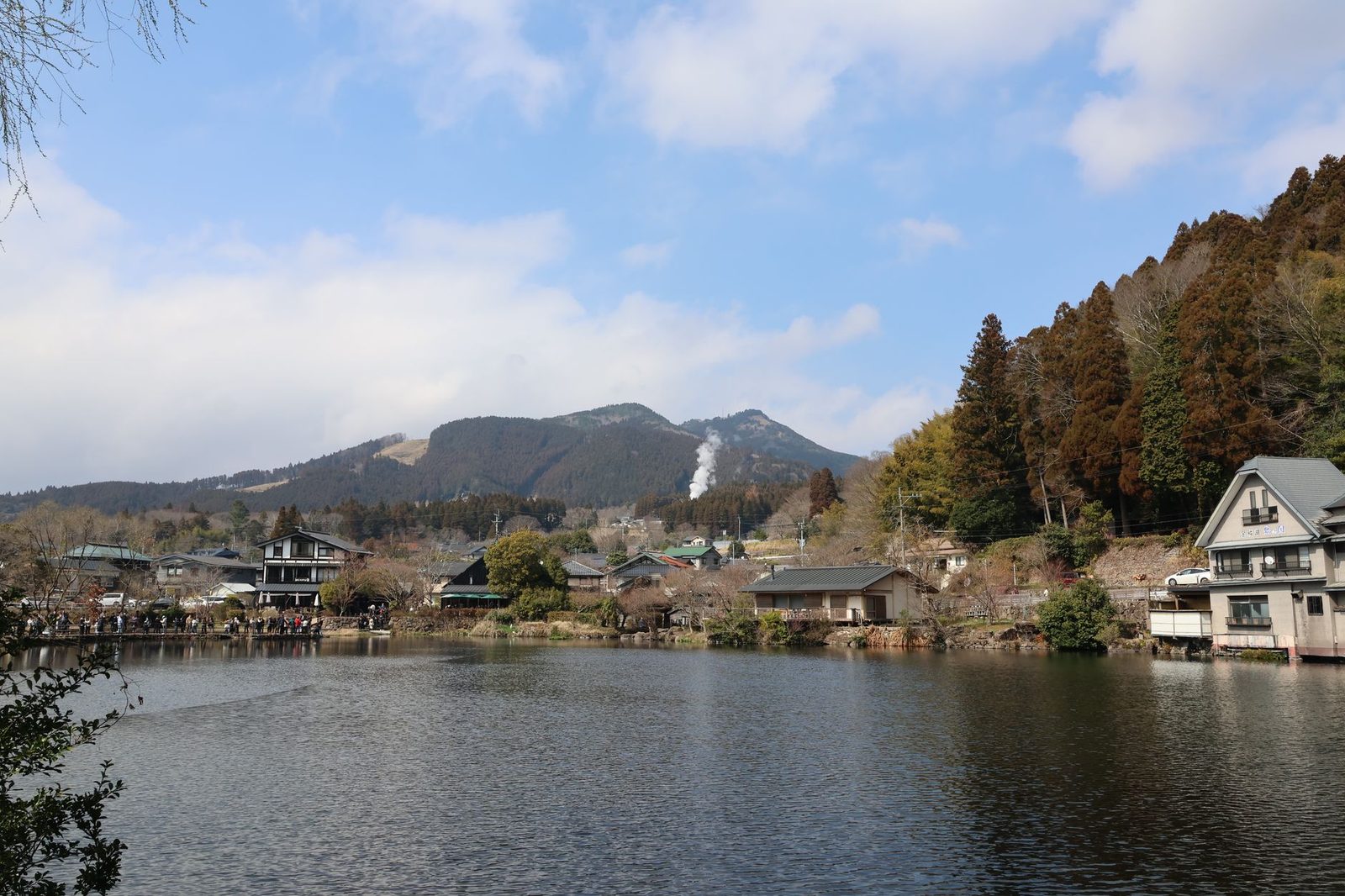 Illustrative photo: Picturesque view of Yufuin with mountains and lakeside houses under a clear sky.