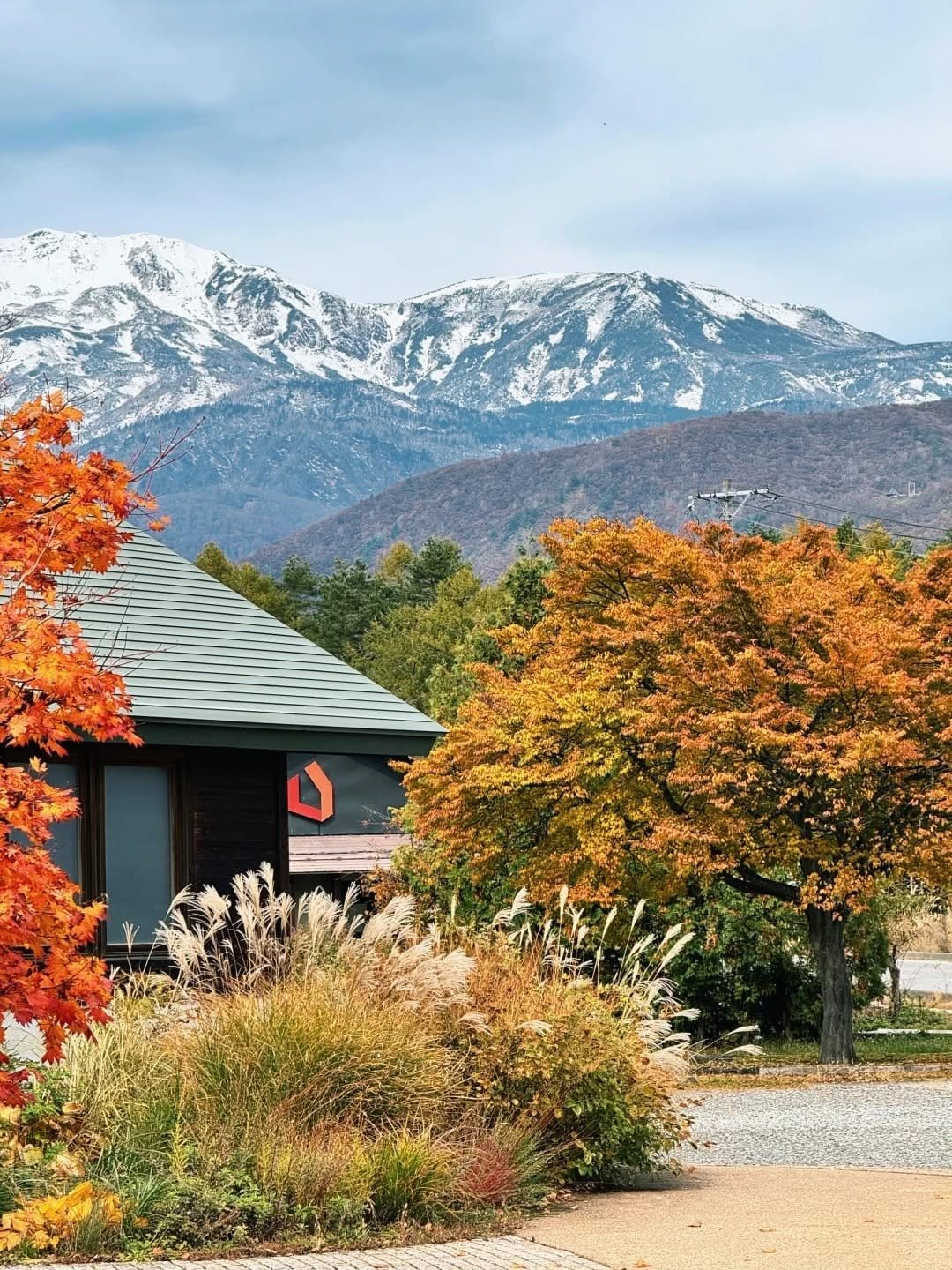 A timber lodge in the Hakuba valley with early snow on the peaks behind